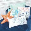 painterly sea turtle and coral on a neutral pillow surrounded by matching coastal pillows on a chair