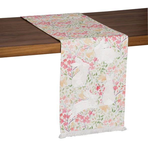 printed and chain stitched runner with a delicate watercolor floral and leaf background, delicate fringe edges, and various leaping, sitting, and standing bunny silhouettes