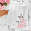 flour sack towel with three bright pink roses and two colorful butterflies flying over top on a marble counter