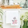 flour sack towel with three bright pink roses and two colorful butterflies flying over top hanging from a counter