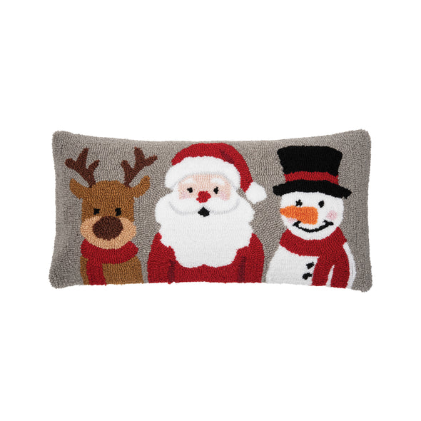 hooked pillow with a reindeer, Santa, and a snowman on top of a grey background