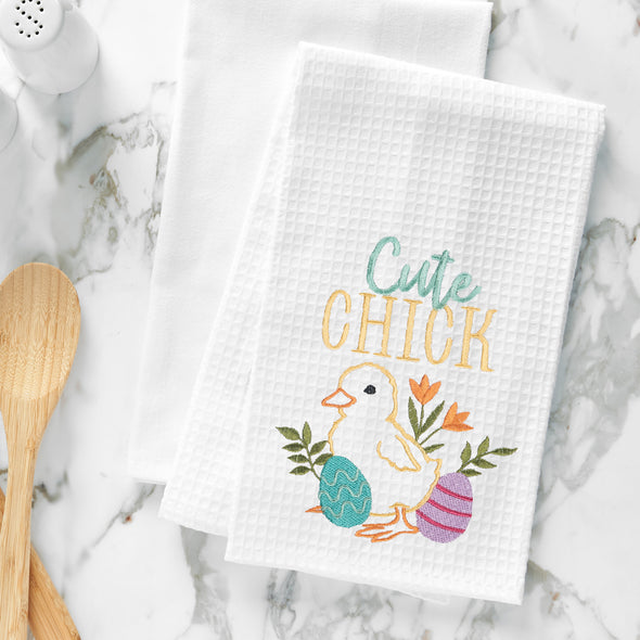 embroidered waffle weave towel with the words cute chick above a yellow chick surrounded by flowers and easter eggs on a marble counter