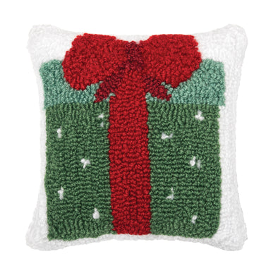 hooked pillow with a green present on a white background. the gift box present has white dots and a bright red bow