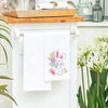 flour sack towel with an adorable bunny holding decorated easter eggs and surrounded by delicate flowers hanging from a kitchen counter