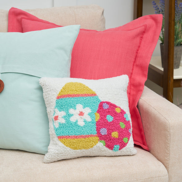 easter egg mini hooked pillow on a couch with a blue and pink pillow