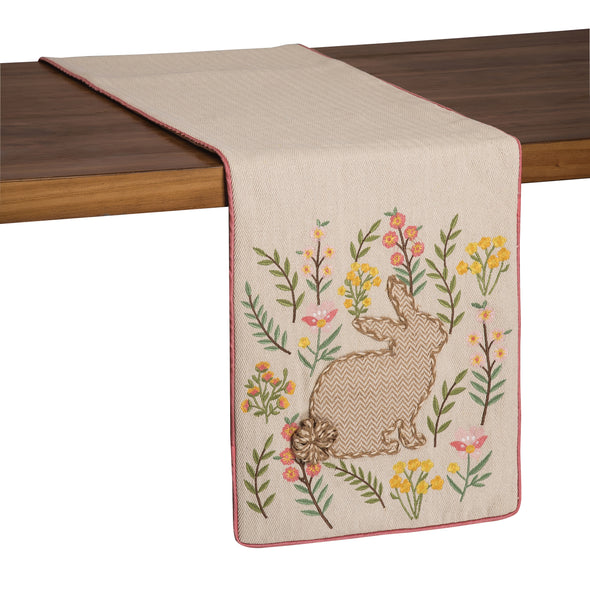 applique and embroidered runner with a natural background and natural and white bunny in the center surrounded by pink and yellow flowers and greenery. the pillow is trimmed in a coordinating pink.