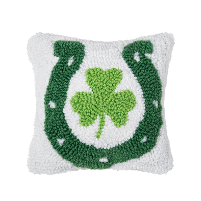 white pillow showing a dark green horseshoe with a small light green shamrock in the middle