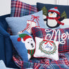 hooked pillow with white ice skates and red laces on a light blue background surrounded by additional winter and Christmas decor on a blue chair