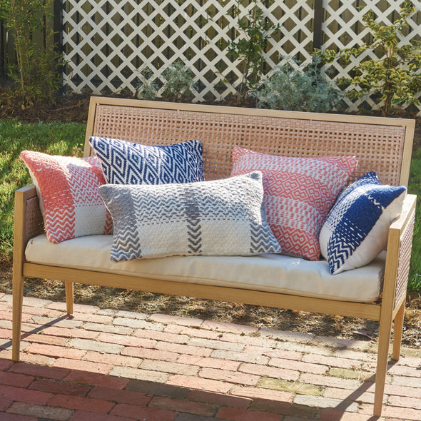 diamond and geometric patterned indoor outdoor pillows on a bench in a garden