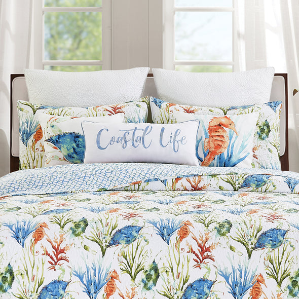 watercolor style bedding collection featuring a crab and seahorse pillow on a bed