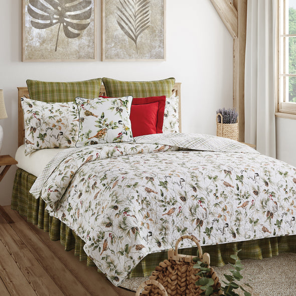 quilt set with chickadees and wrens perched among twigs of green leaves, acorns, berries, and pinecones that reverses to a coordinating plaid