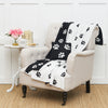 black knit pillow with white paw prints on a chair paired with a matching throw showing both sides of this reversible print