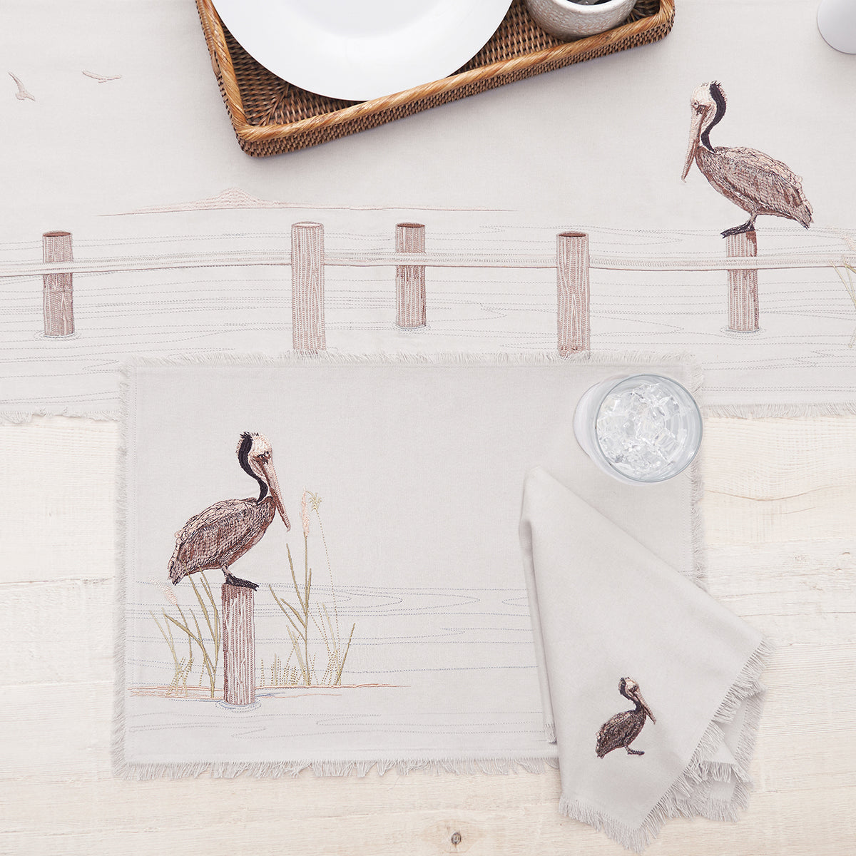 Table setting with placemats and napkins featuring bird designs on a light background.