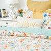 quilt with a watercolor inspired wildflower print in vibrant red, yellow, and blue flowers that reverses to a coordinating blue with an abstract foliage style print