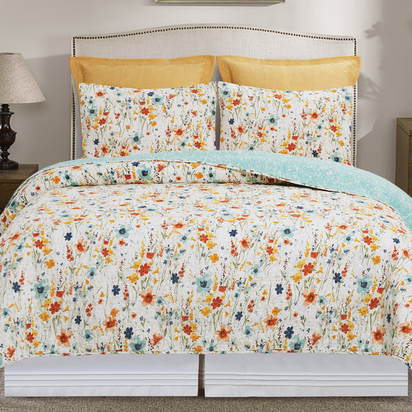 quilt with a watercolor inspired wildflower print in vibrant red, yellow, and blue flowers that reverses to a coordinating blue with an abstract foliage style print