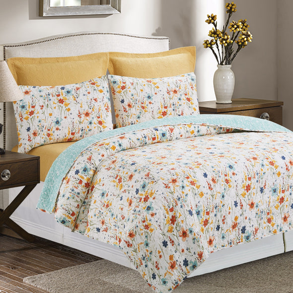 quilt with a watercolor inspired wildflower print in vibrant red, yellow, and blue flowers that reverses to a coordinating blue with an abstract foliage style print