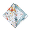 quilted table linens with a watercolor inspired pattern of wildflowers in bright colors including red, orange, and blue that reverses to a coordinating blue and a simple abstract foliage style pattern