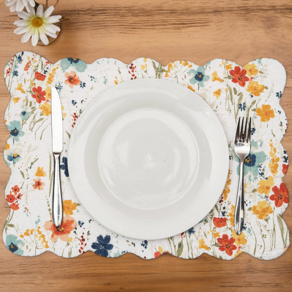 quilted table linens with a watercolor inspired pattern of wildflowers in bright colors including red, orange, and blue that reverses to a coordinating blue and a simple abstract foliage style pattern