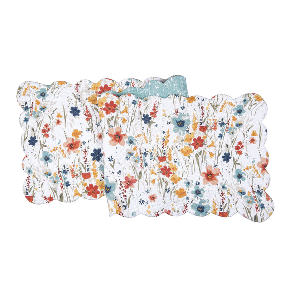 quilted table linens with a watercolor inspired pattern of wildflowers in bright colors including red, orange, and blue that reverses to a coordinating blue and a simple abstract foliage style pattern