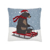 hooked pillow depicting a brown bear wearing a red hat and scarf sledding down a snowy hill on a red sled