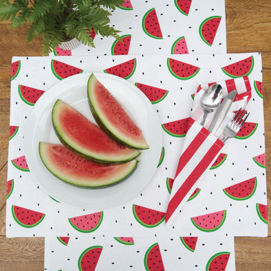 printed table linens with watermelon slices surrounded by little black seeds paired with a red and white striped napkin