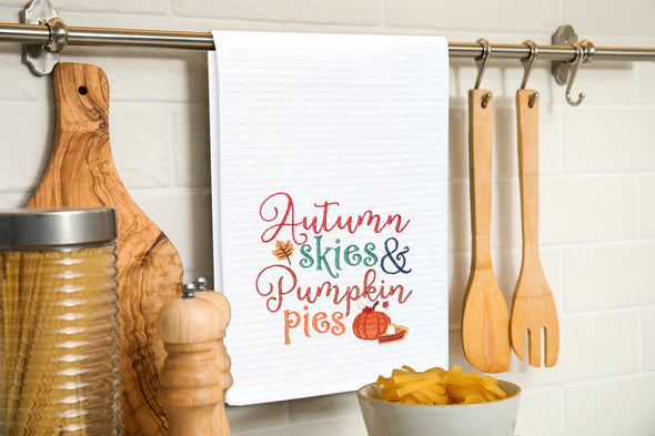 Embroidered Autumn Skies & Pumpkin Pies kitchen towel hung over a kitchen utensil bar.