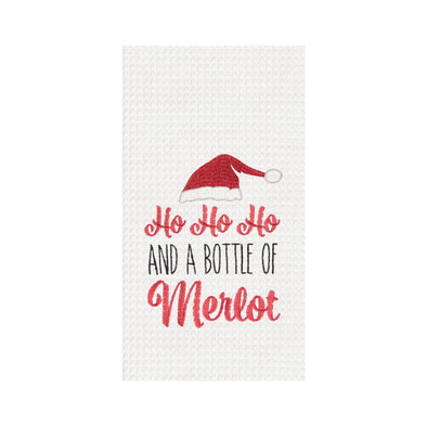 bottle of merlot waffle weave kitchen towel, santa hat over the words ho ho ho and a bottle of merlot on a white towel