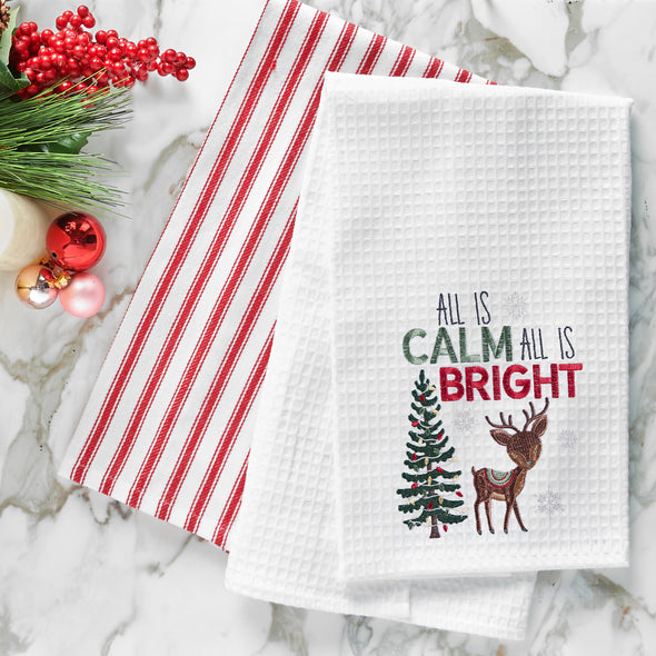 waffle weave towel with the phrase All is Calm All is Bright above an adorable reindeer next to a decorated Christmas tree on a marble countertop