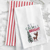 waffle weave towel with the phrase All is Calm All is Bright above an adorable reindeer next to a decorated Christmas tree on a marble countertop