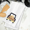 white waffle weave towel with a black truck filled with candy corn and the phrase trick or treat on a marble countertop