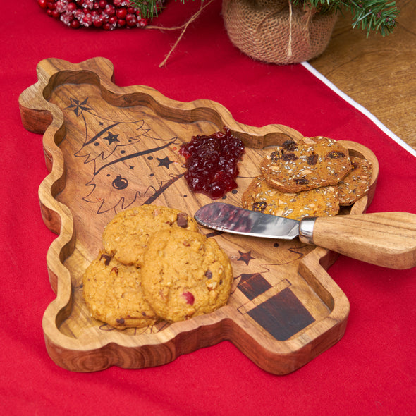 christmas shaped serving board made from acacia wood with a spreader on a table with a red runner