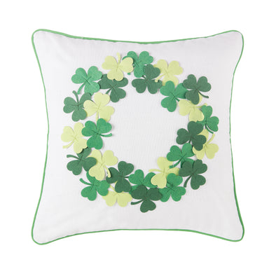 white pillow with green pipping around the edges with a wreath featuring clovers in different shades of green