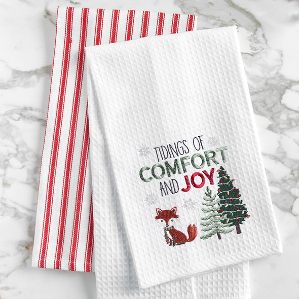 waffle weave towel with the words tidings of comfort and joy above a fox and christmas trees on a marble countertop