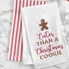 embroidered flour sack towel with a gingerbread man cookie on top and the phrase cuter than a Christmas cookie below in different fonts on a marble countertop