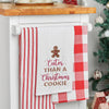 embroidered flour sack towel with a gingerbread man cookie on top and the phrase cuter than a Christmas cookie below in different fonts hanging from a kitchen countertop