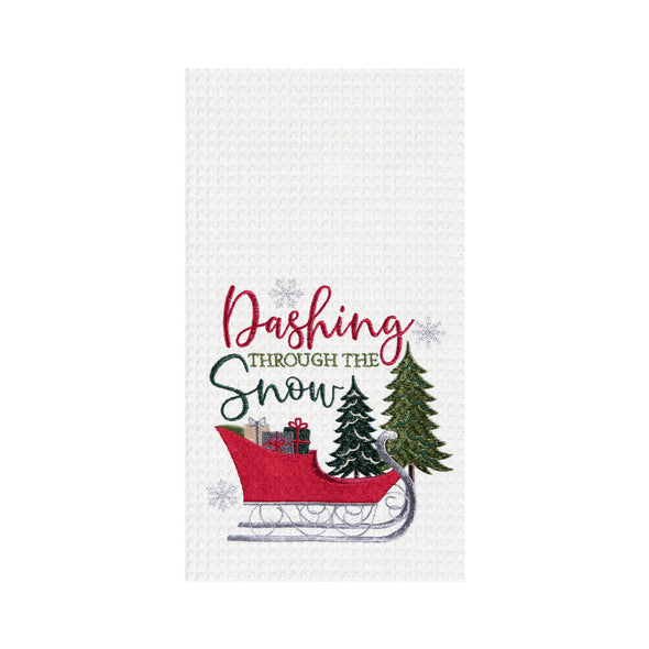 waffle weave towel with the phrase Dashing through the Snow in flourishing script above a red sleigh filled with presents gliding through the forest