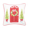 Door Wreath Pillow has a red door with a wreath hanging on the door surrounded by decorative trees on a white pillow with red trim