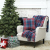 woven plaid throw and pillow with a navy red and white plaid design on a chair next to a tree and presents