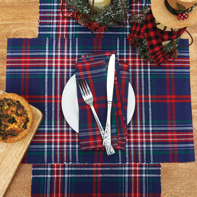 woven table linens featuring a navy blue green red and white plaid pattern on a wooden table surrounded by food and holiday decor