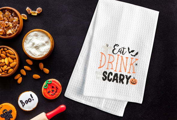 Embroidered Eat, Drink and be Scary kitchen towel styled on in a Halloween themed flatlay.