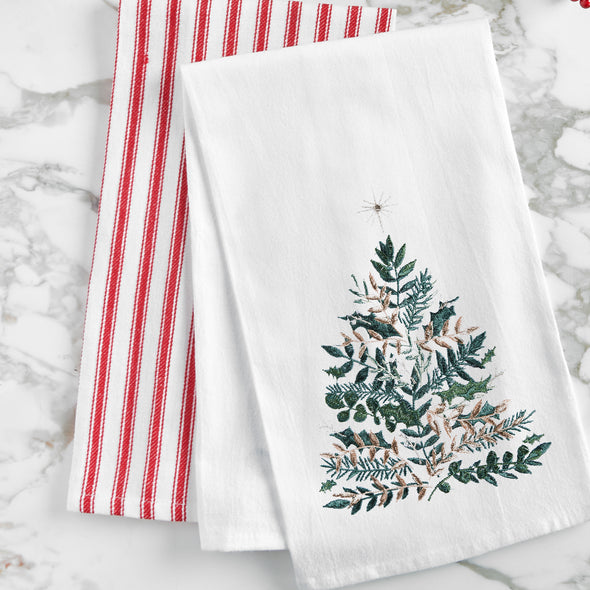 embroidered flour sack towel with artwork by Lori Siebert of an emerald Christmas tree with gold accents and a simmering star on top on a marble countertop