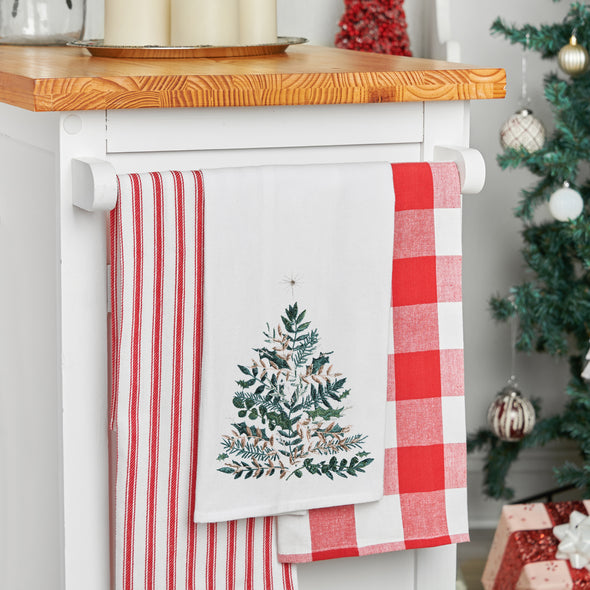 embroidered flour sack towel with artwork by Lori Siebert of an emerald Christmas tree with gold accents and a simmering star on top hanging from a kitchen countertop