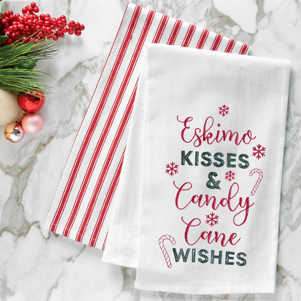 embroidered flour sack towel with the phrase eskimo kisss and candy cane wishes surrounded by snowflakes and candy canes on a marble countertop