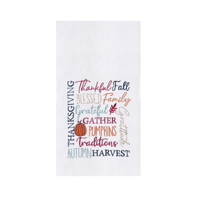 flour sack towel with harvest related words in different font styles arranged in different directions. decorative elements like pumpkins and foliage are added in the mix