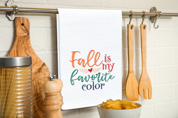 Embroidered Fall is my Favorite Color kitchen towel hung on a kitchen utensil bar.