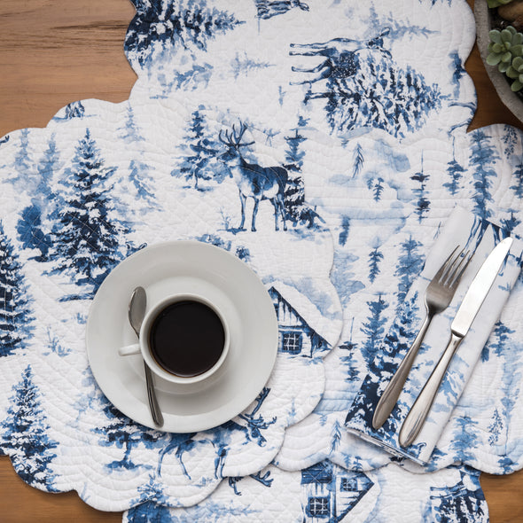 quilted table linens with a blue watercolor inspired forest scene on a wood table with a cup of coffee