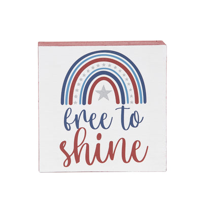 shelf block with the text that says free to shine and a rainbow shape of red and blue stripes paired with silver stars