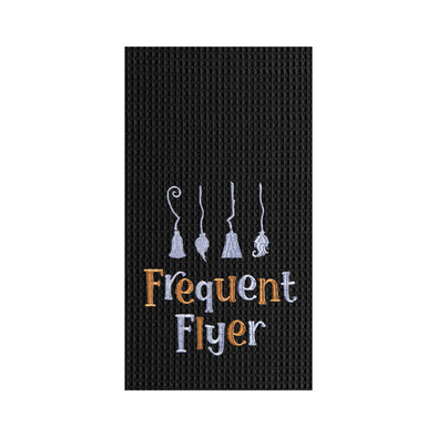 black embroidered waffle weave towel with four brooms and the phrase Frequent Flyer