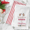 embroidered flour sack towel with the phrase gingerbread kisses and Christmas wishes below a gingerbread man and gingerbread woman on a marble countertop