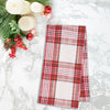 red and white plaid woven kitchen towel on a marble countertop next to holiday decor